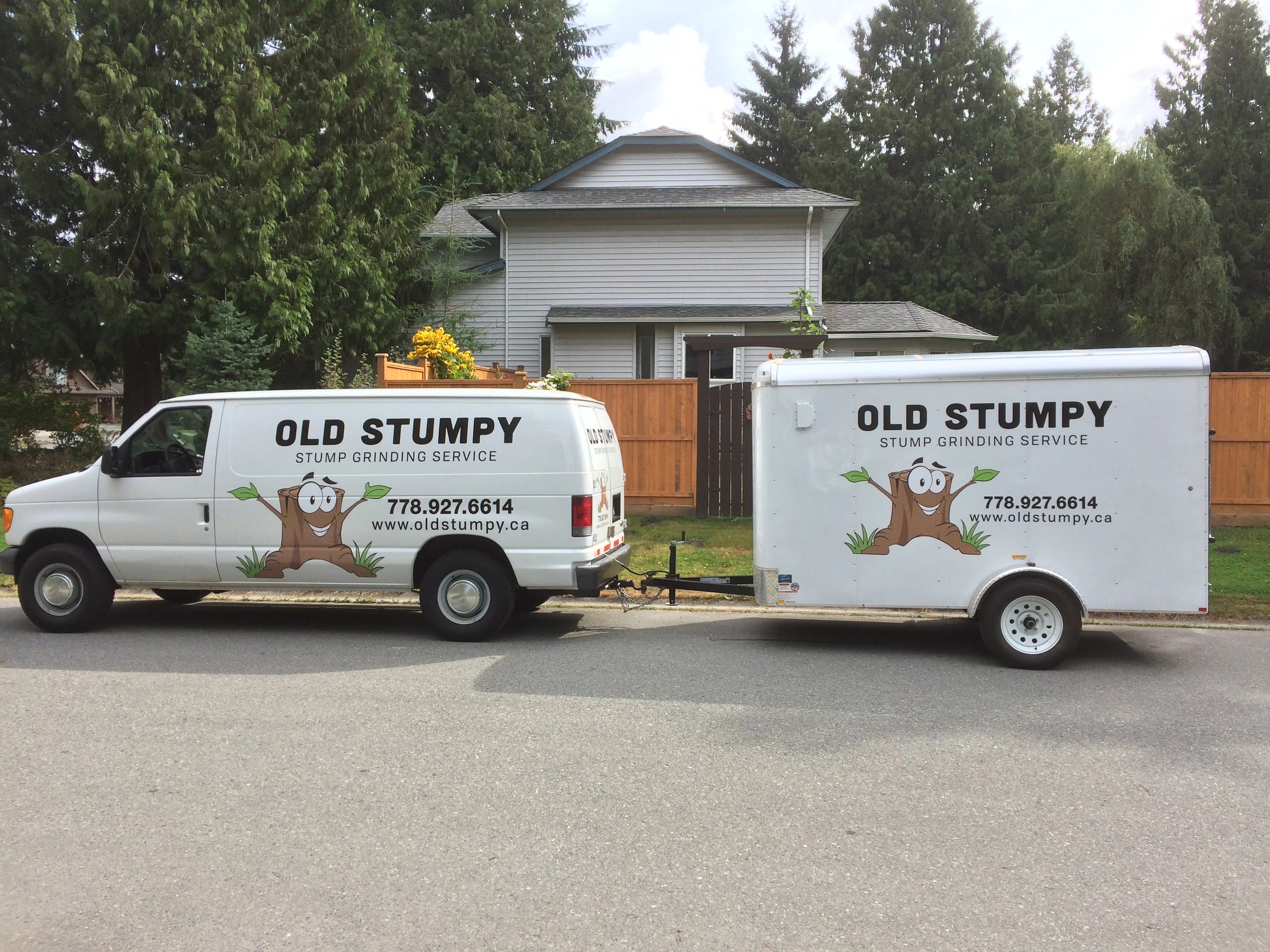 A white work van from "Old Stumpy Stump Grinding Service" is parked on a street in Maple Ridge, BC, towing a matching trailer.