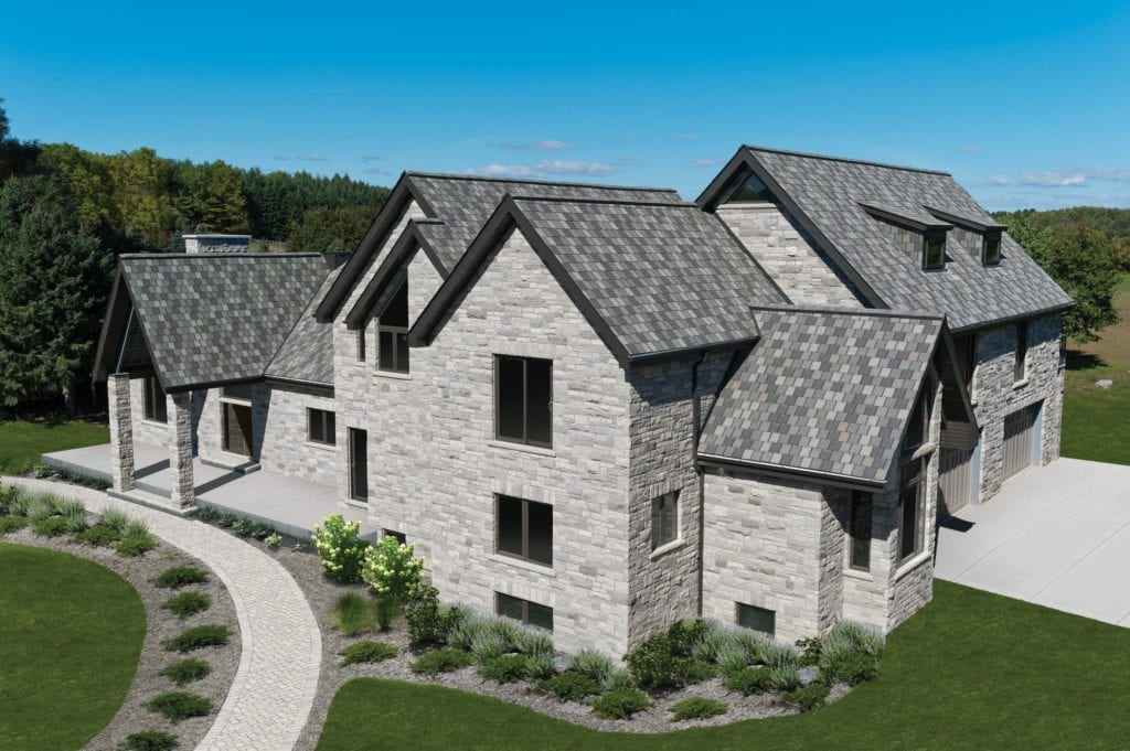 Aerial view of a light stone house with a patterned gray roof in Maple Ridge BC.