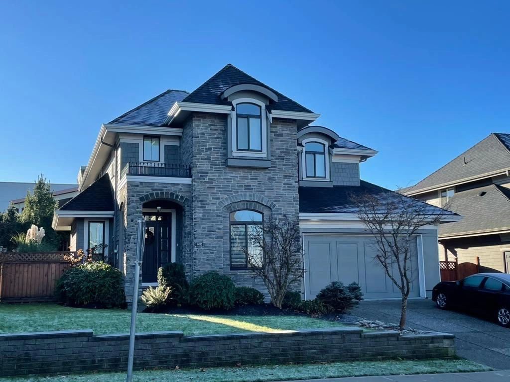 A two-story house in Maple Ridge BC has a gray stone facade, a black roof, and an attached garage.