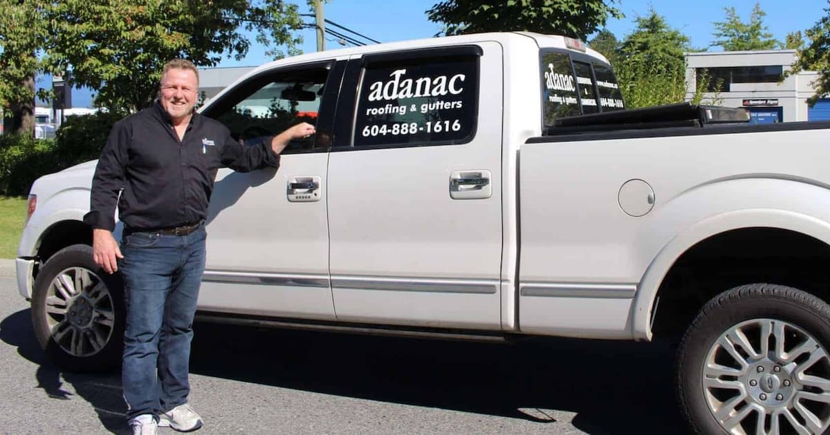 A man stands next to a white pickup truck with "adanac Roofing & Gutters" and a phone number on the door, Maple Ridge BC.