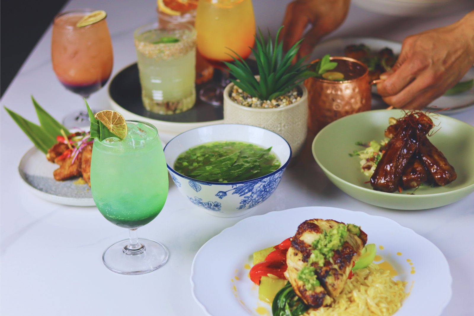 A spread of Halina cocktails and shared Filipino plates on a white table